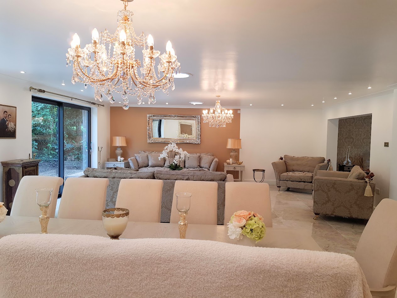 Living and dining room with chandeliers, pale sofas and a dining table
