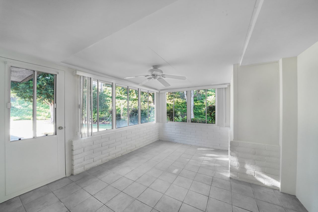 Bright tiled room with large windows overlooking greenery